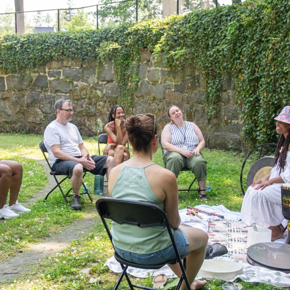 persons sitting outside participating in a music meditation circle