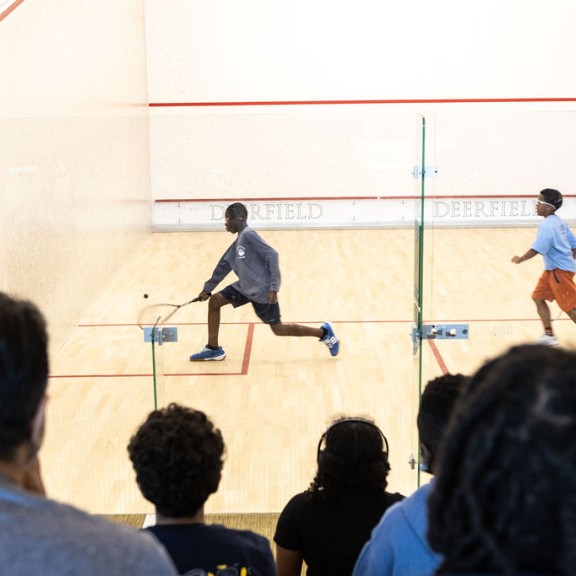 two players playing squash while observers watch in crowd