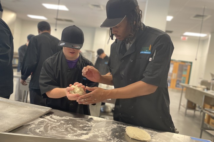 two persons in a culinary class making dough.