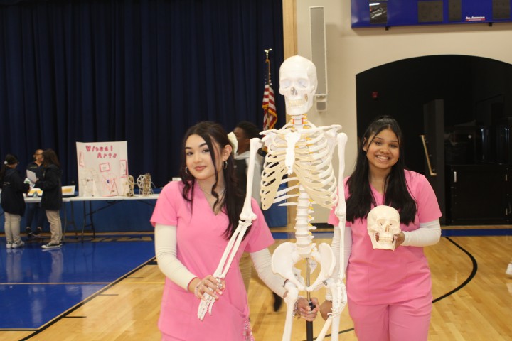 two students working with a mock skeleton for training purposes.
