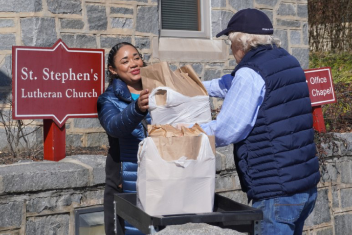 a person handing a distribution of items to another person outside of a lutheran church.