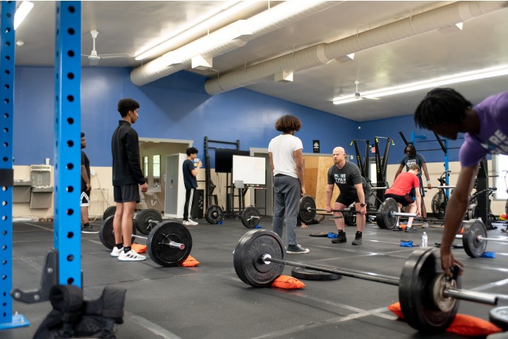 youth lifting weights in a gym with an instructor
