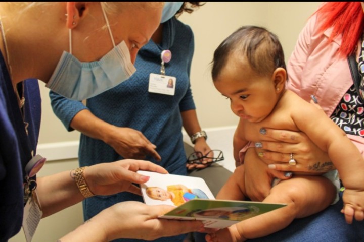 doctors and health staff reading to a child in a patient room with their parent.